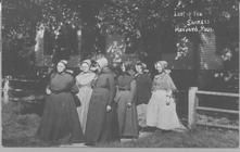 SA0203 - On front: "Last of the Shakers, Harvard, Mass." Six women, some of whom are identified, on a walkway outside a shaded building.